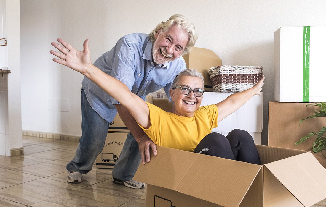 Old man pushing old lady in a cardboard box