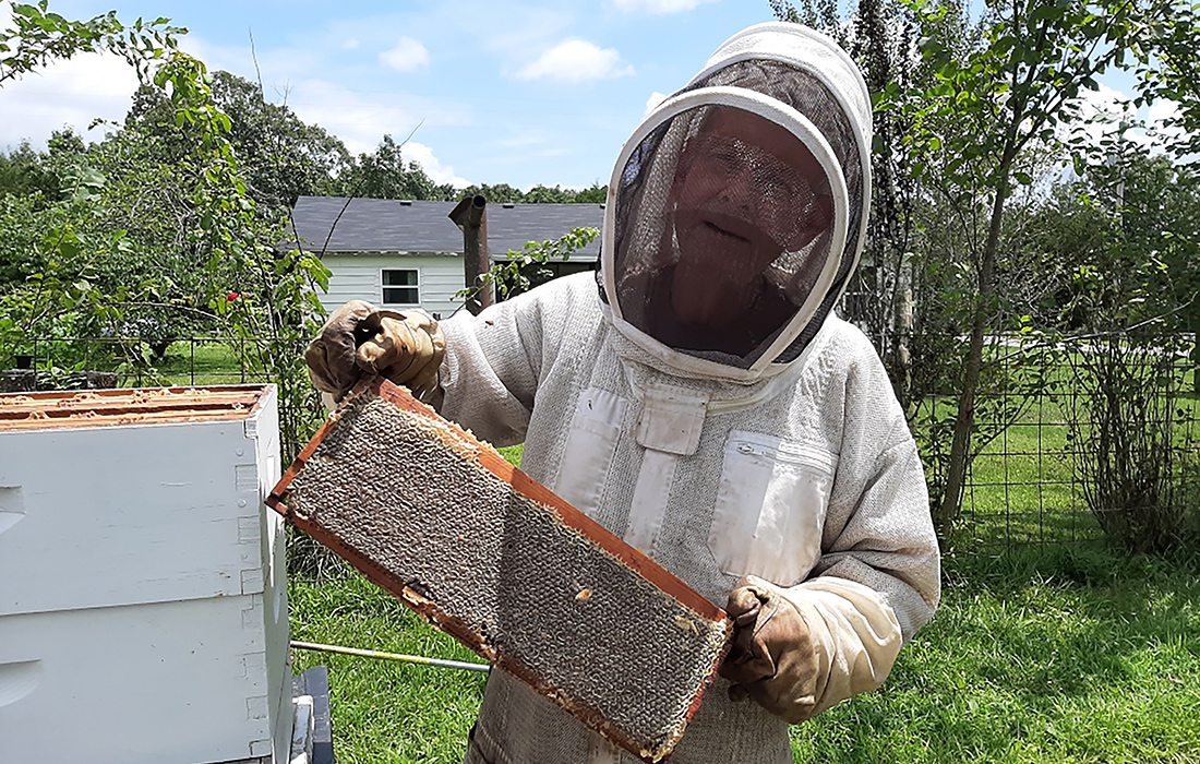 Man in beekeeping suit holding a beehive