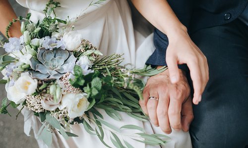 closeup of bride and groom's hands and bridal bouquet