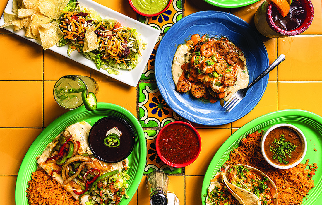 A spread of Mexican food on a tiled table.