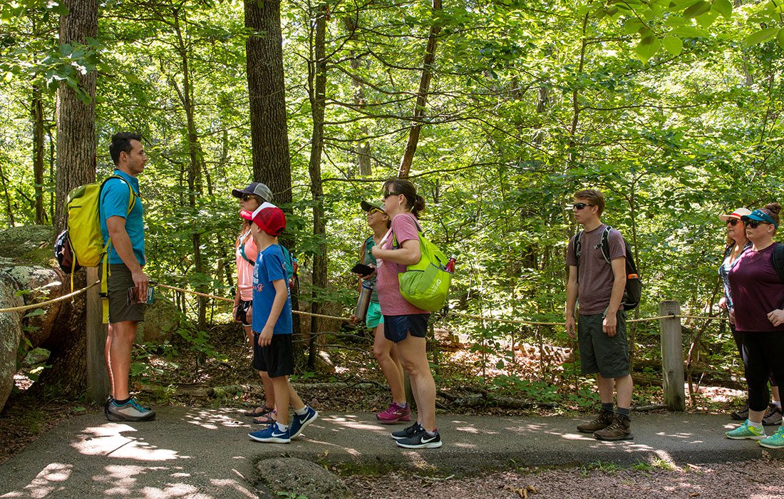 Man giving instructions to a group of people while on a hike in the woods