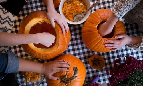people carving pumpkins and seeds in a bowl