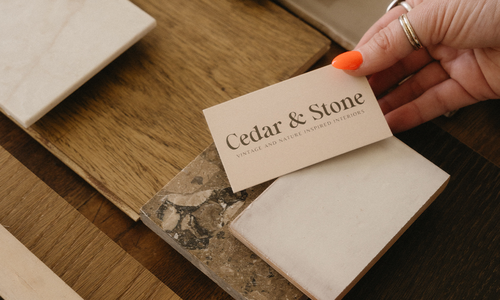 Cedar & Stone business card displayed with natural stone and wood material samples for interior design selections.
