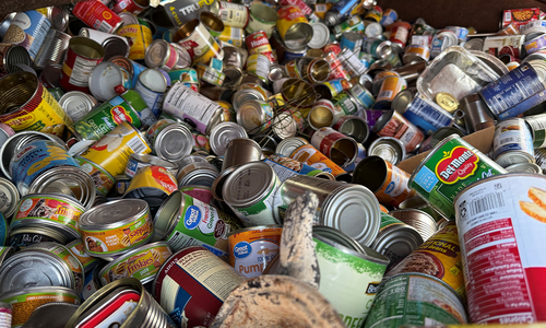 A recycling bin piled high with empty, opened food and pet food cans.