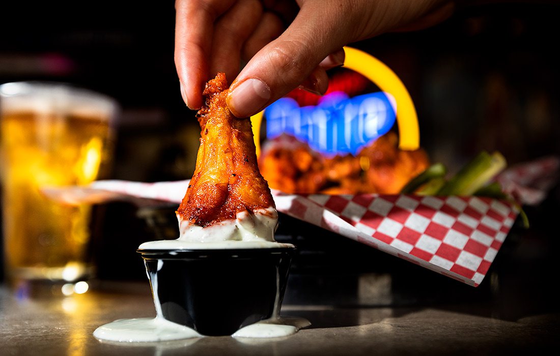 Spicy hot buffalo wings being dipped into ranch dressing at Coyote's Adobe Cafe in Springfield MO