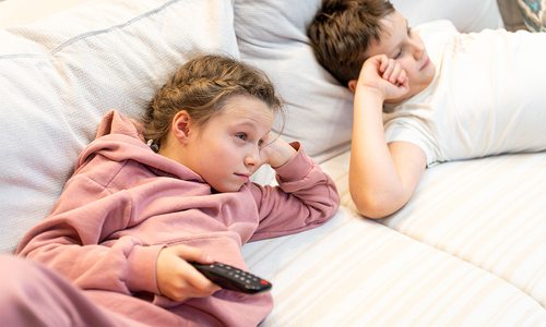 Kids watching TV on the couch.