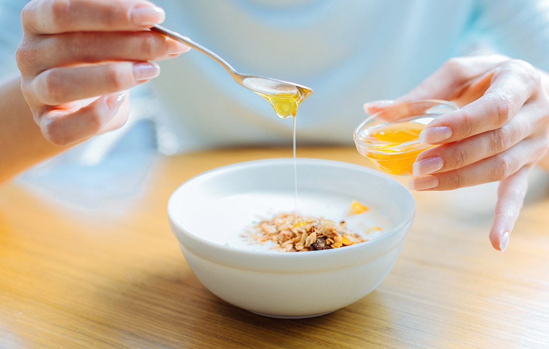 Woman drizzling honey over her bowl of oatmeal