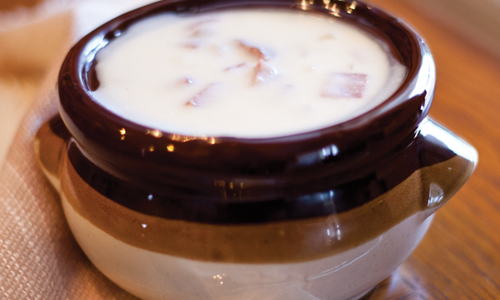The creamy potato soups sits in a ceramic bowl
