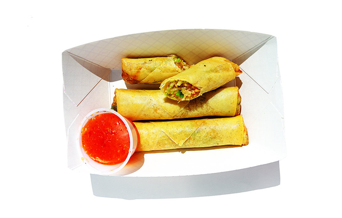 Egg rolls with sweet-and-sour sauce in a paper box.