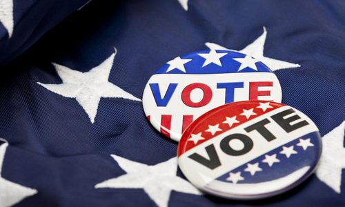 Two "vote" buttons lying on an American flag