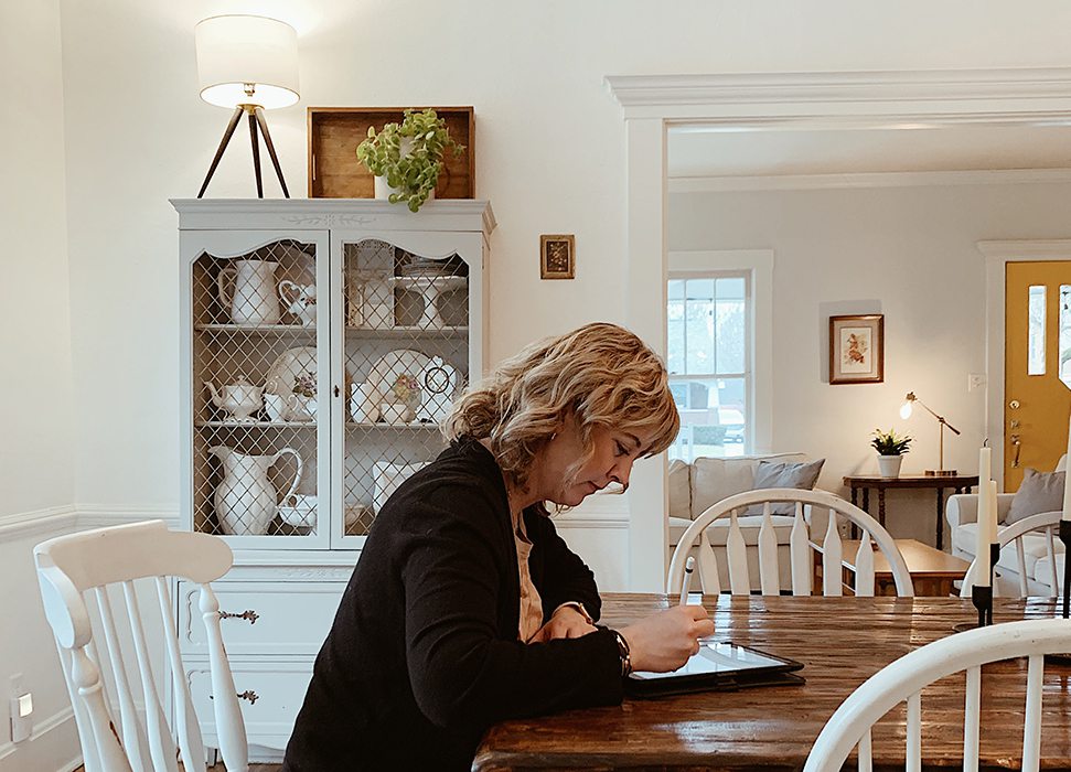 Jen Jeppsen looks at her ipad at her kitchen table