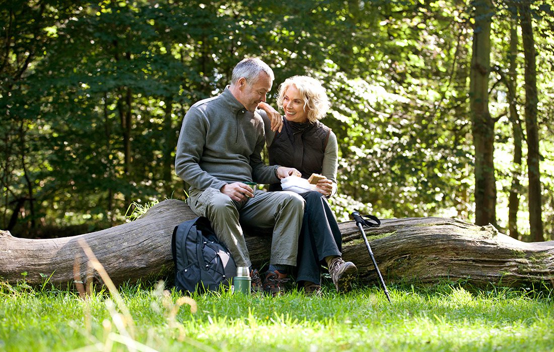 Mature couple enjoying a sandwich while on a hike