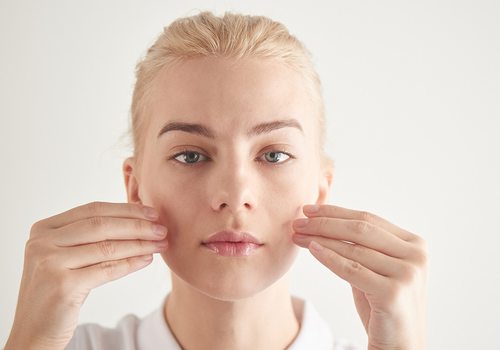 Young woman doing yoga exercises with her face