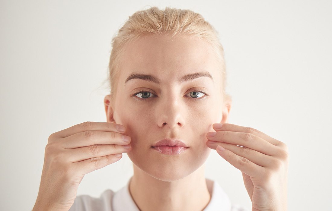 Young woman doing yoga exercises with her face