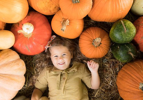 Young girl surrounded by pumpkins at Pickin' Patch Farm