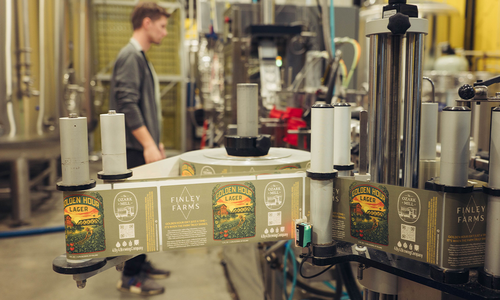 Golden Hour Lager labels move through a labeling machine during production.