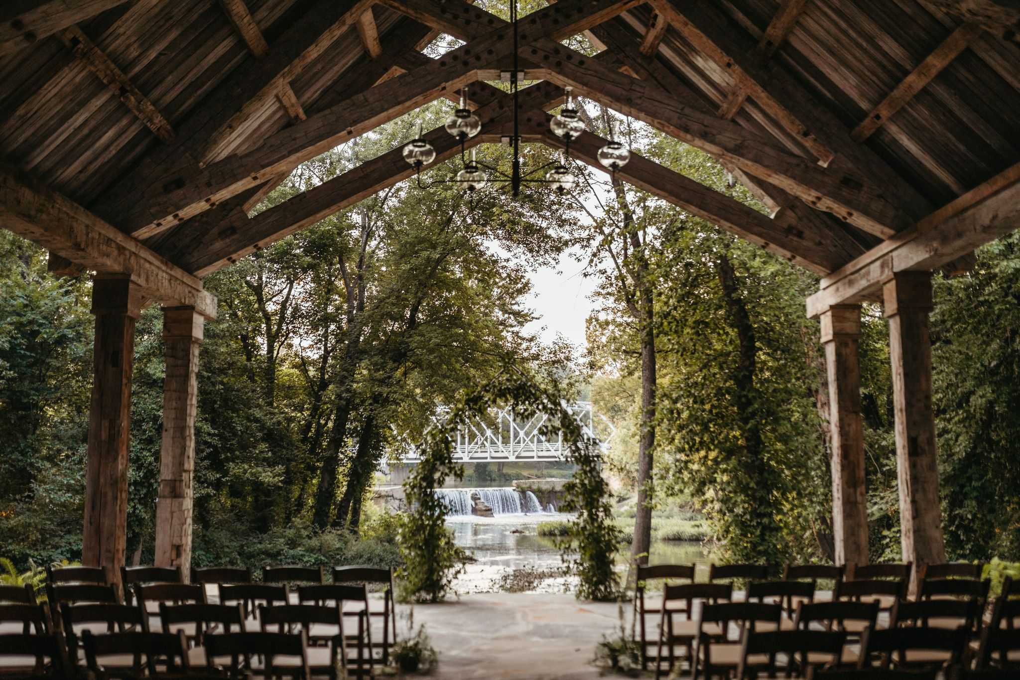 An outdoor wedding chapel overlooks the Finley River, the Riverside Bridge and rushing waterfalls.