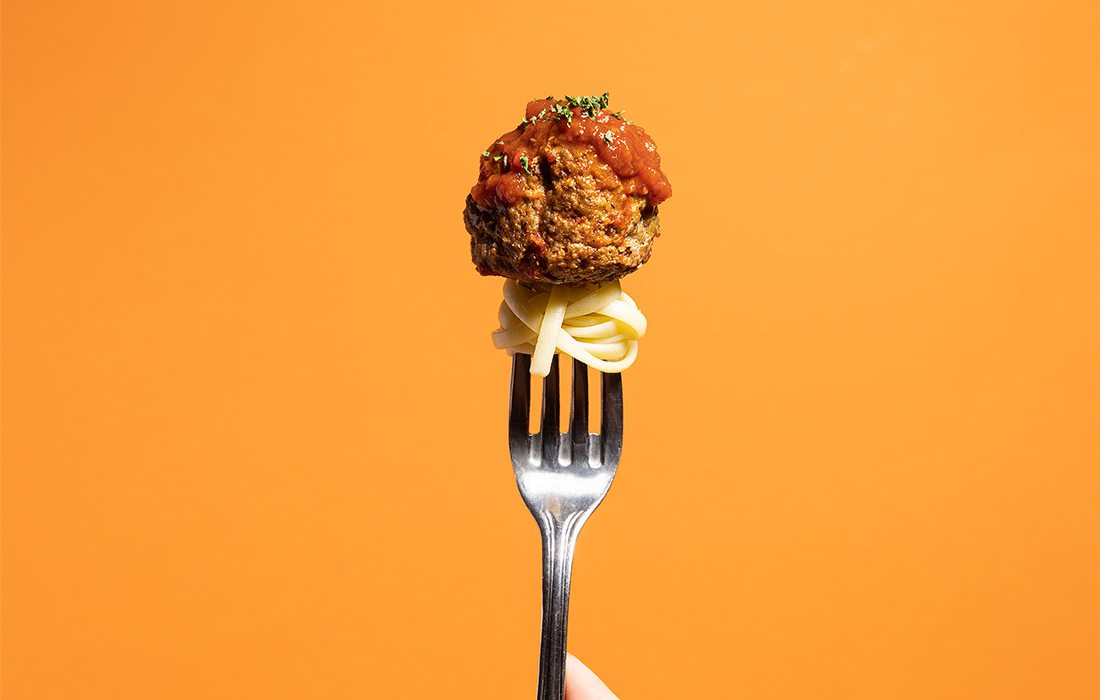 Meatball on a fork with pasta.