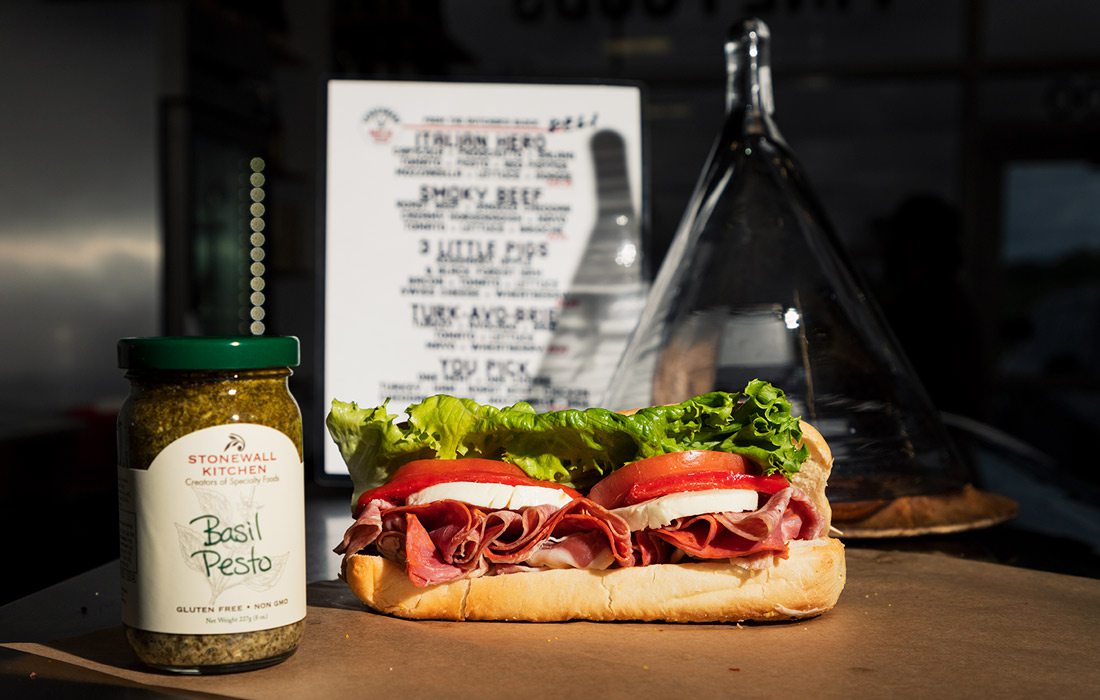 Sandwich next to basil pesto bottle