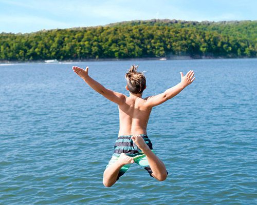 Boy jumping into lake