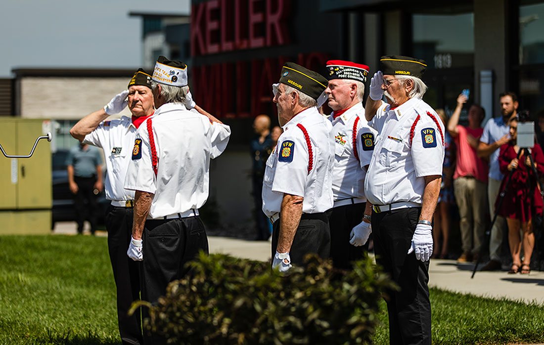 Men in military uniforms salute the flag.