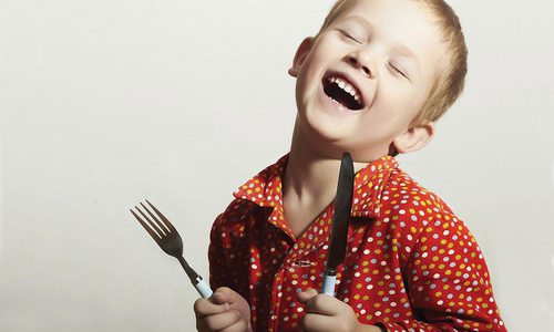 kid with a fork and a knife learning etiquette