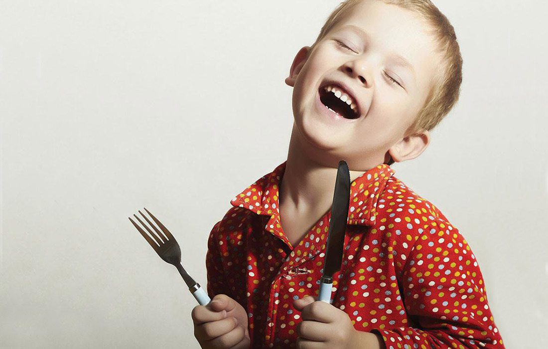 kid with a fork and a knife learning etiquette