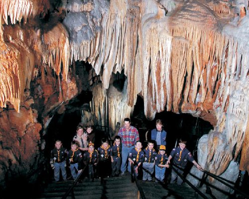a group of boys and their adult guide smile among the huge caverns surrounding them