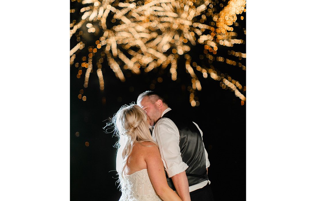 A couple kissing during a firework show.