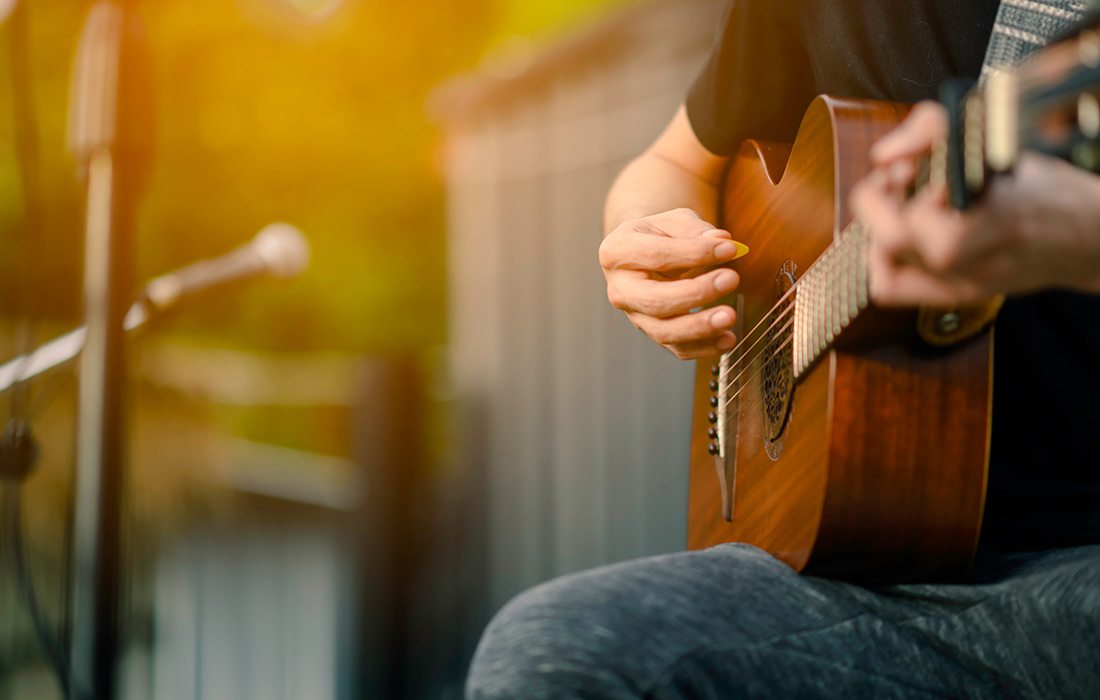 Closeup of someone playing an acoustic guitar outside