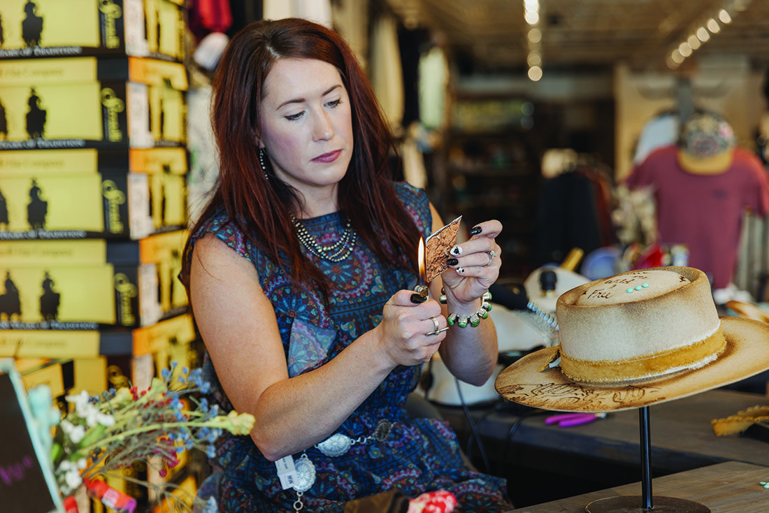 A woman holds a lighter up to a blunt piece of shiny material.