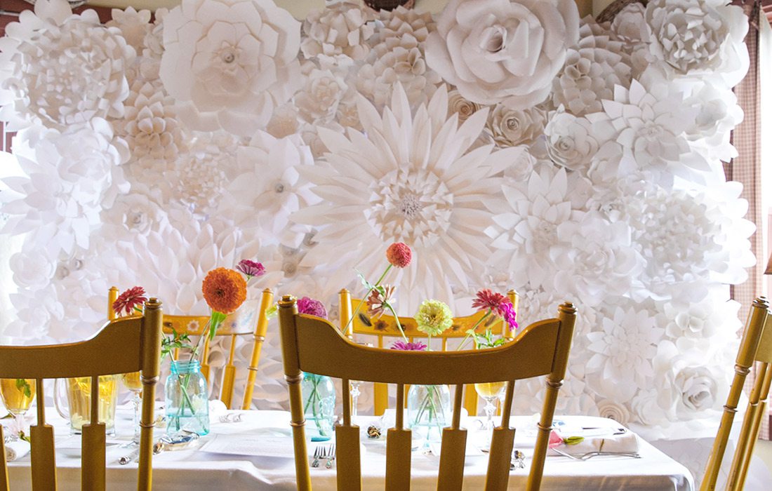 White flower arrangements over table and chairs.