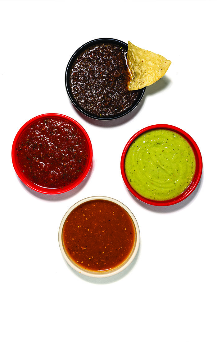 Four sauces in little bowls, two red, one green, one brown.