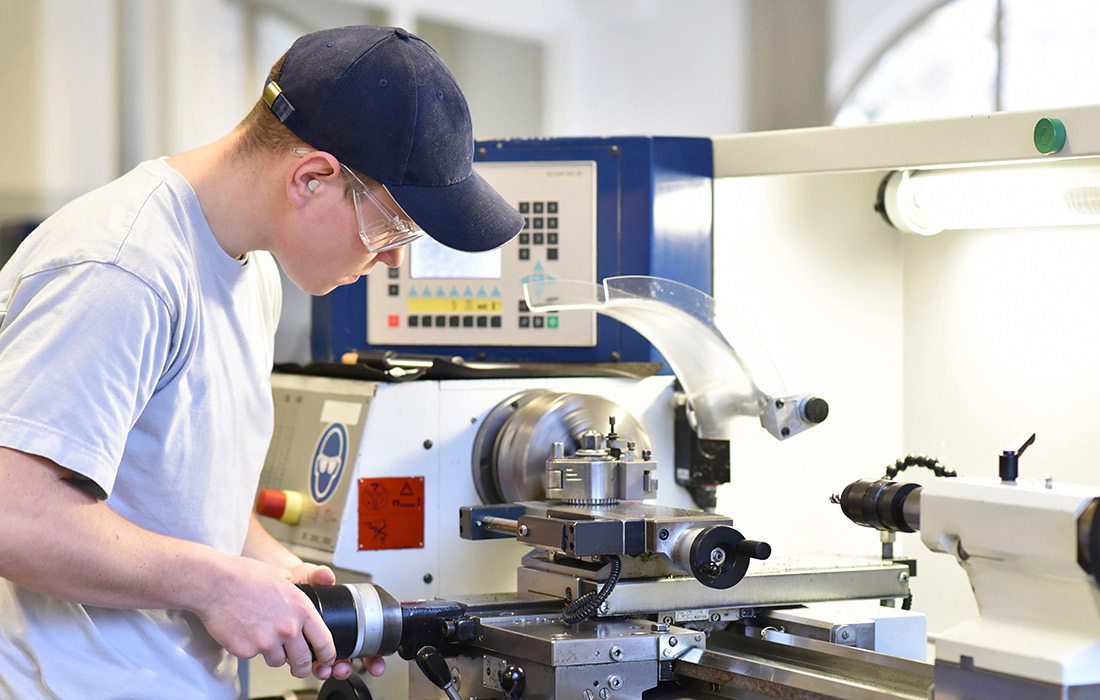 young apprentice in vocational training working on a turning machine in the industry