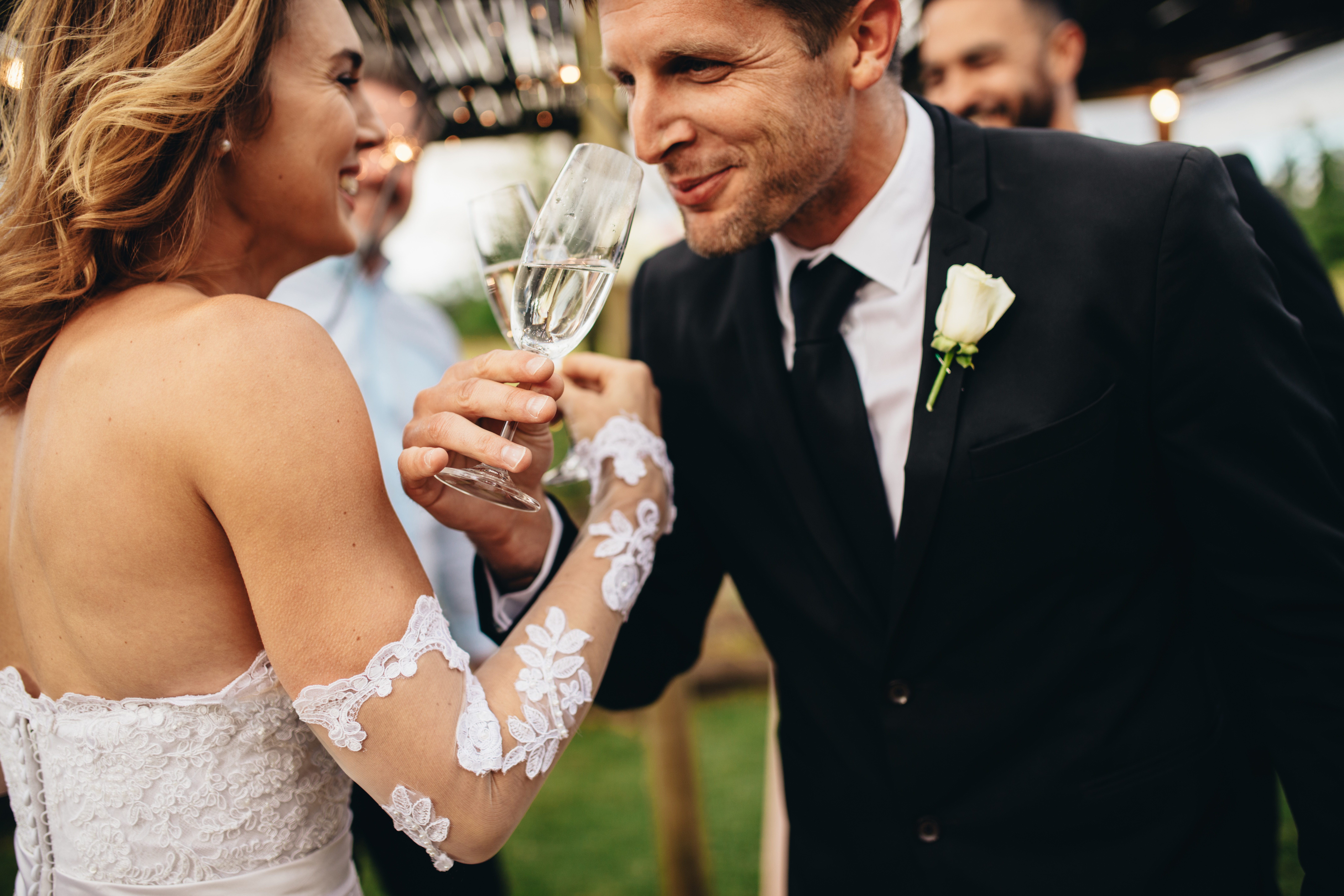 A bride and groom link arms in a champagne toast.