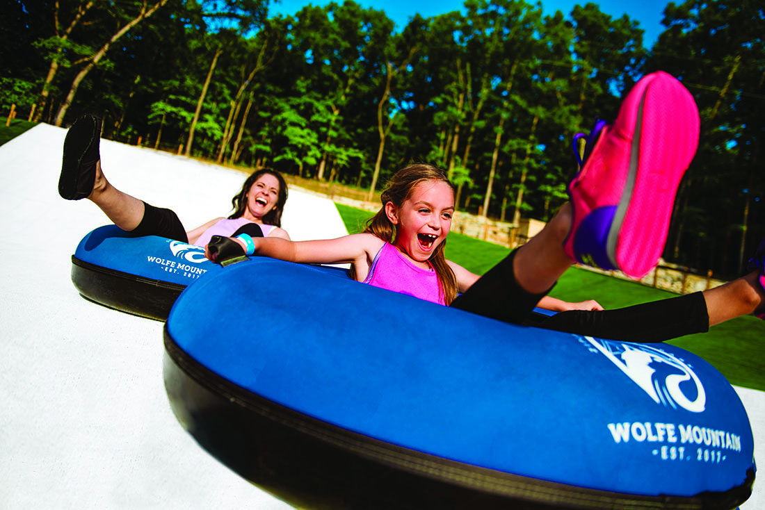 A woman and a girl sliding down a hill on inner tubes.