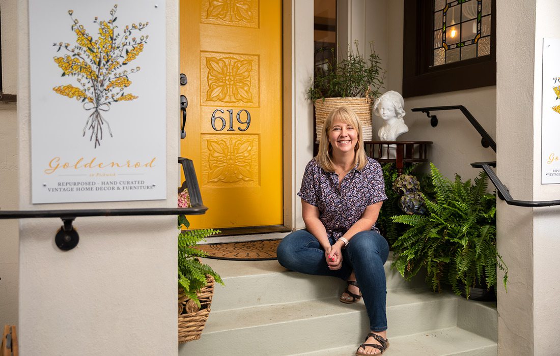 Jen Jeppsen sits in front of yellow door at Goldenrod