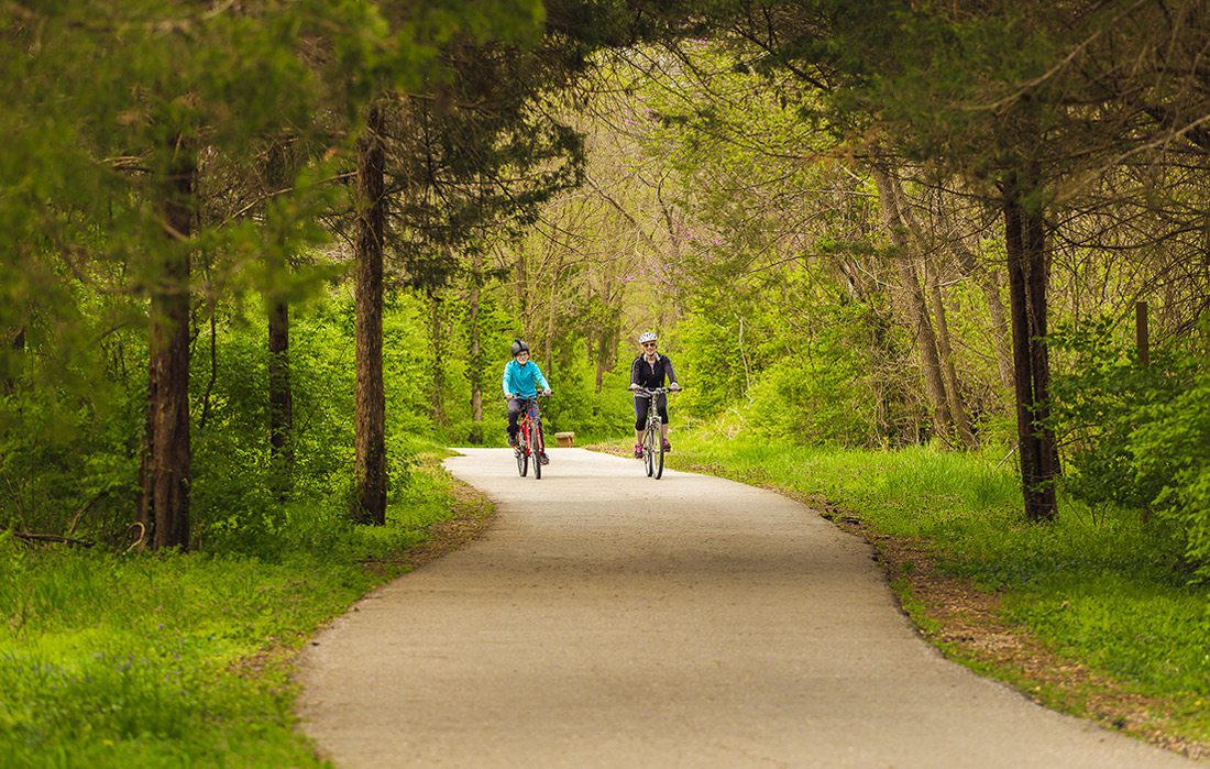 two people bike down trail