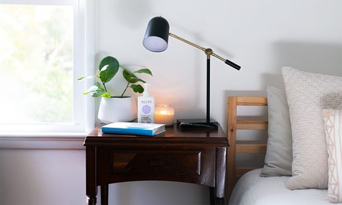 nightstand with lamp, plants and a book
