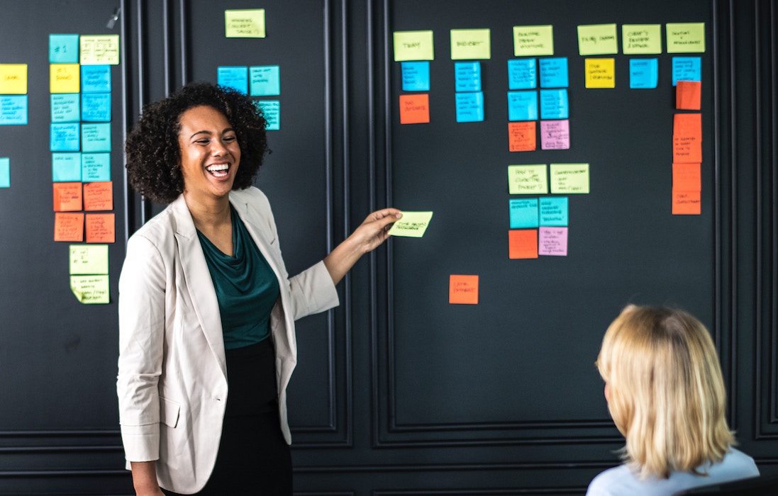 a business women uses sticky notes as a visual aid while leading a presentation