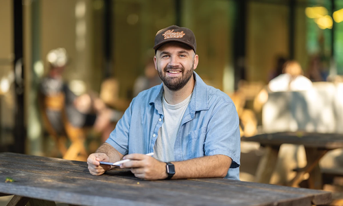 Camp Ape founder Andrew Lovell at an outdoor coffee-shop table.