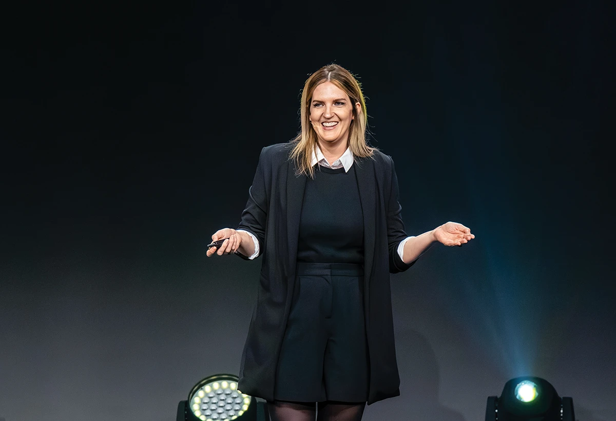 Habit coach Katie Day speaking on stage at a keynote event.