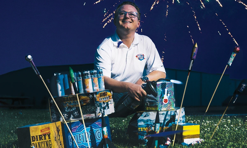 Michael Ingram stands in front of a fireworks display