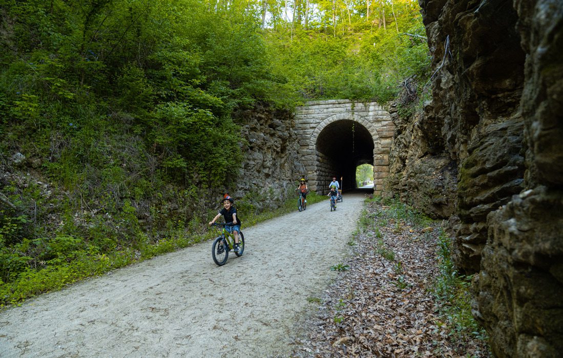 family rides bikes through tunnel on bike trail