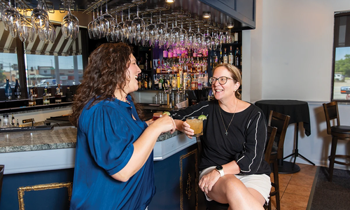 Simply Delicious Catering owner Patty Wingo and Biz 417 editor Dori Grinder at a bar.