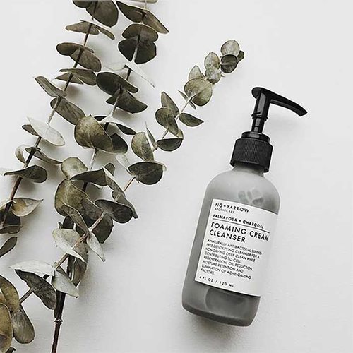 bottle of product next to three stems of eucalyptus