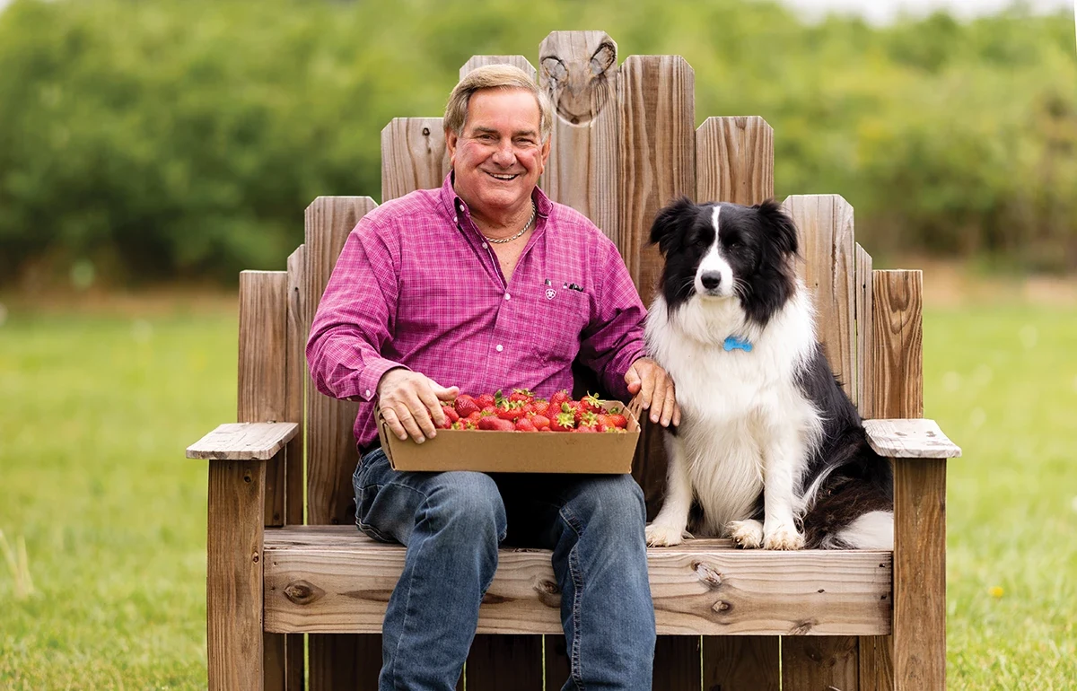 Randy Little sits on a bench with a dog at Missouri Berries