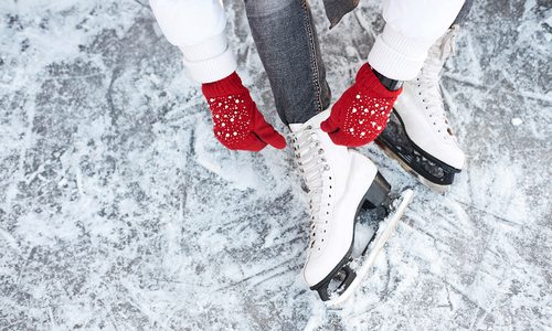 Lacing up ice skates with red gloves