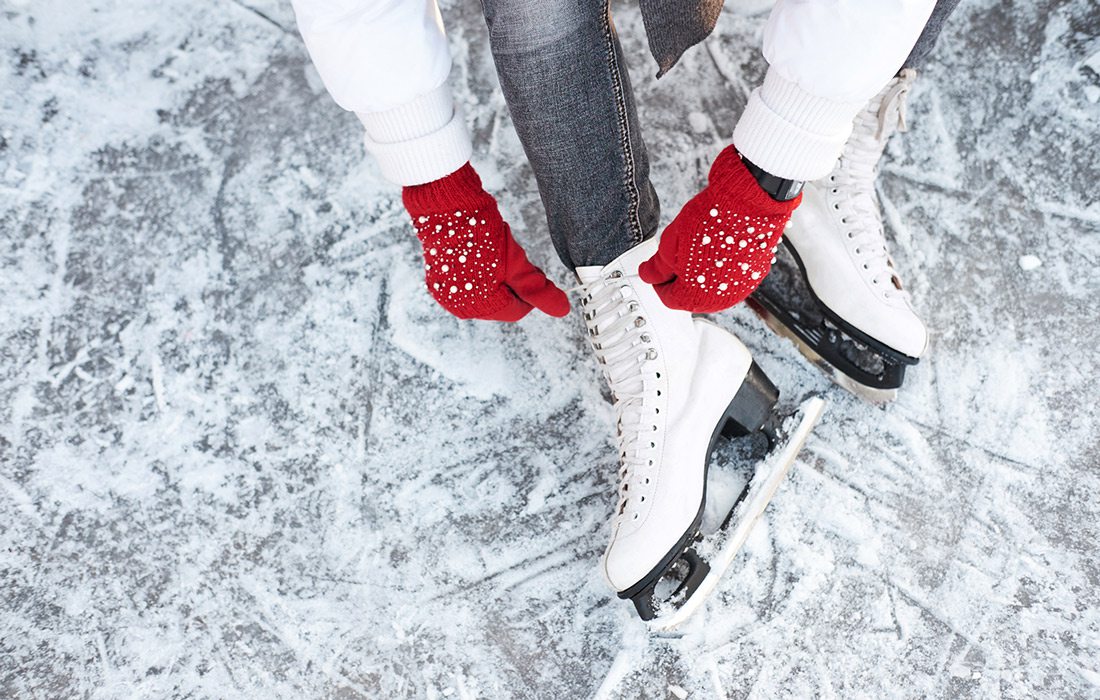 Lacing up ice skates with red gloves