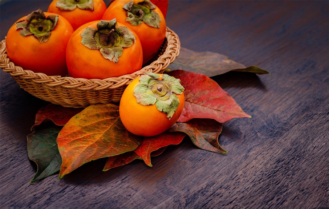 Persimmons on a table with fall leaves
